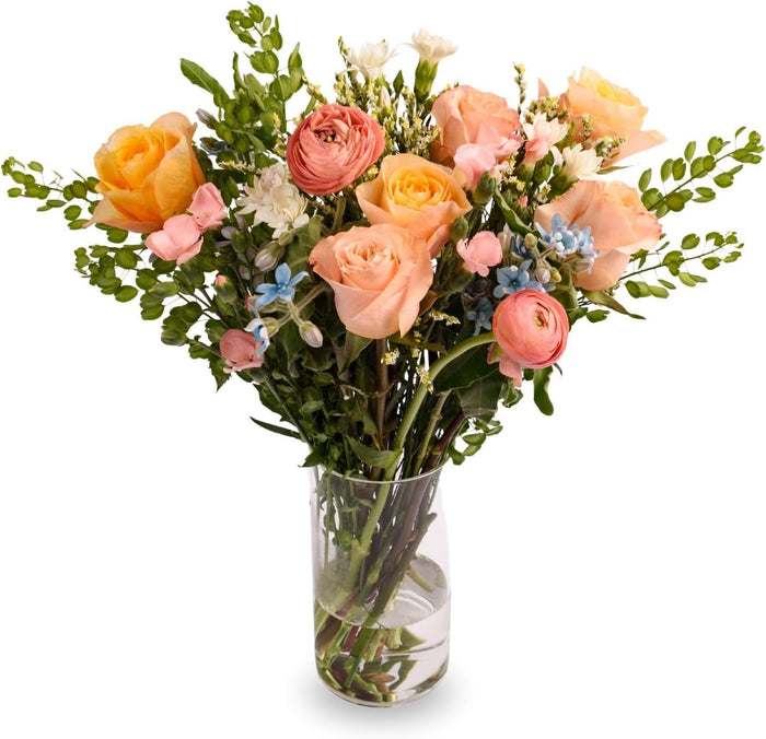 Sky Dream bouquet with peach roses and blue accents in a glass vase