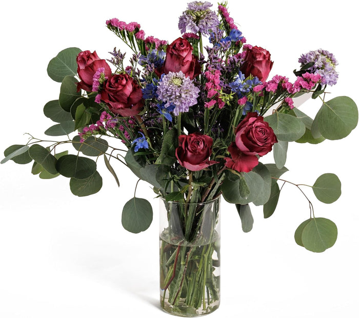 Midnight Garden bouquet with burgundy roses and blue accents in a glass vase